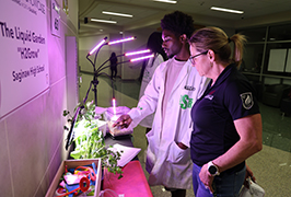  A boy and a woman look at plants under a growligqt.